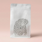 White coffee bag with a black line drawing of a dog's face on a pink background