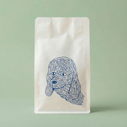 White coffee bag with blue dog illustration on a light green background