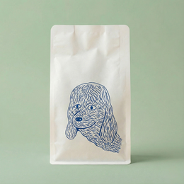 White coffee bag with blue dog illustration on a light green background