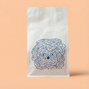 White paper bag with a blue dog illustration on a peach background