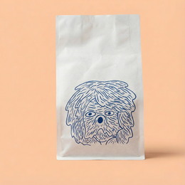 White paper bag with a blue dog illustration on a peach background